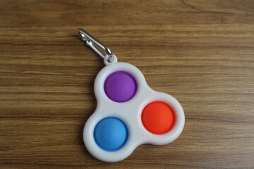 TOYs Popit SIMPLe DIMPLe A little spinner on a ri cell on a wooden background with a place for text...