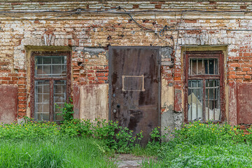 Fototapeta na wymiar shabby brick wall, windows and locked door of abandoned old factory