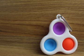 TOYs Popit SIMPLe DIMPLe A little spinner on a ri cell on a wooden background with a place for text...