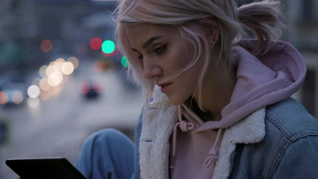Girl With Tablet In Her Hands. Cute Young Girl With Pink Hair On The Background Of The Evening City.