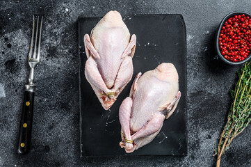 Farm eco friendly raw quails ready for cooking. Black background. Top view