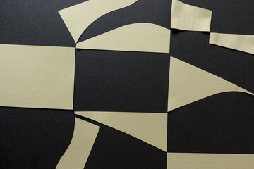 isolated and flat pale yellow paper shapes on dark grey board - photographed from above in a flat lay style
