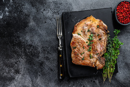 Grilled Pork Loin Steak On A Marble Board. Black Background. Top View. Copy Space