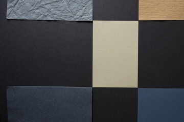 pieces of yellow-ochre and grey paper arranged in a slight checkered pattern on a grey board -...