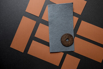 brown and grey paper rectangles on dark grey board with a rusty metal washer - photographed from...