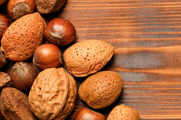 Almonds, walnuts and hazelnuts on a brown wooden background.