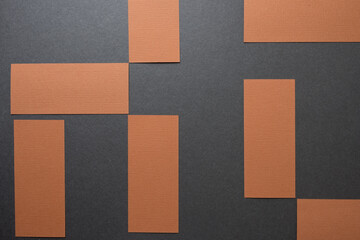 brown construction paper rectangles arranged in a checkered pattern on dark grey board - photographed from above in a flat lay style