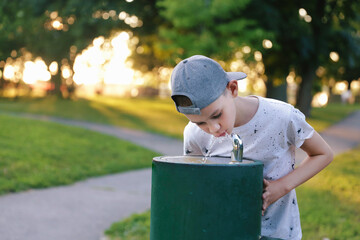 Boy drinks tap water from public drinking fountain. Free space for your text