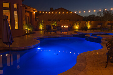 Fototapeta na wymiar A night shot of a desert landscaped house in Mesa Arizona with an outdoor fireplace, pool and spa.
