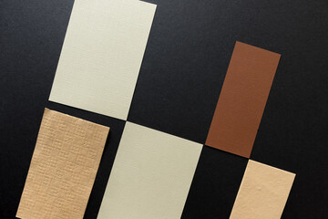 pieces of yellow-ochre and brown paper arranged in a partial checkered pattern on a grey board - photographed from above in a flat lay style