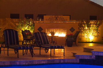 A night shot of a desert landscaped house in Mesa Arizona with an outdoor fireplace, pool and spa.