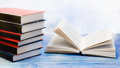a stack of books and an open book lie on a blue wooden table