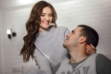 A beautiful woman and her beloved boyfriend are having fun at home. Love relationship between a man and a woman. Close-up portrait of a young family dressed in home clothes