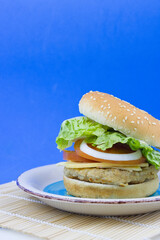 Hamburger on a plate on blue background and copy space