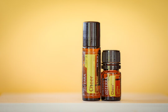 Doterra Cheer essential oil roll on and 5ml bottle on display. Vibrant yellow background with copy space.