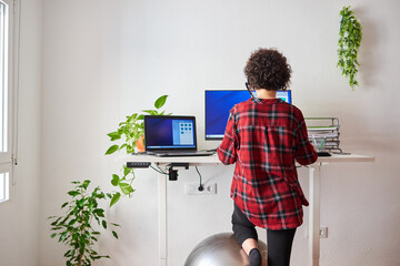 Unrecognizable woman teleworking at an adjustable standing desk - Powered by Adobe