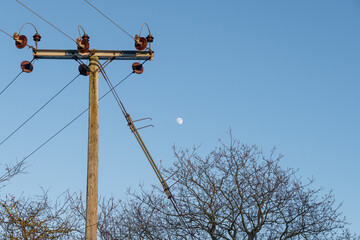 Moon by a power line in rural countryside during clear skies