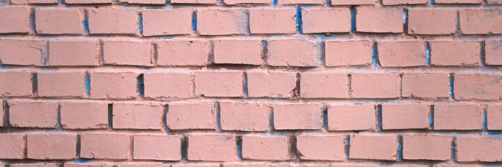 Obraz premium Old brick wall painted in pink. Texture of rough brickwork. Wide panoramic background with masonry.