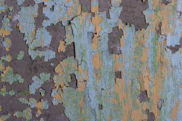 Peeling paint on the wall. Old concrete wall with cracked flaking paint. Weathered rough painted surface with patterns of cracks and peeling. Grunge texture for background and design. High resolution.
