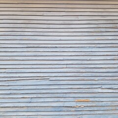 An entire side of a garage with worn grey wooden siding. 