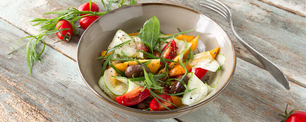 a bowl of salad with tomatoes, cucumbers and tarragon on a wooden table