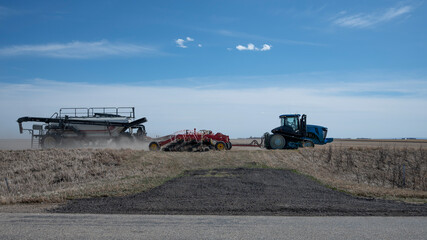Fototapeta premium Farmer in his tractor in the field beginning the spring planting and fertilizing for a autumn harvest of crops in Canada. 