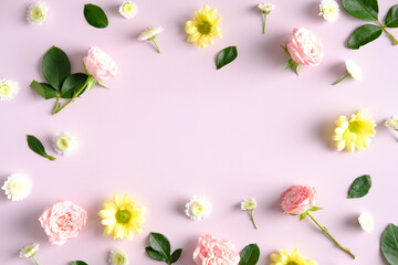 Frame made of spring flowers and green leaves on pink background. Floral flat lay composition.