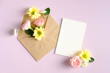 Envelope with flowers and blank paper card mockup on pink background. Happy Valentines day, Mothers day, birthday concept. Romantic flat lay composition.