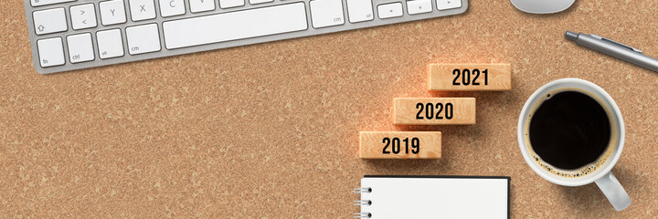 cubes forming a stair with year numbers on every step, beginning with 2019 and ending with 2021 surrounded by office equipment on cork background