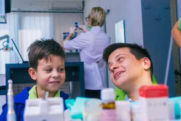 Obraz premium Two happy young brothers sitting in a dentist office and waiting for a dental examination