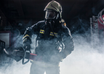 Obraz premium Portrait of a fireman wearing firefighter turnouts and helmet. Dark background with smoke and blue light.