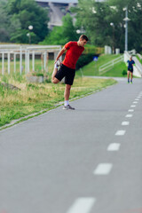 Handsome young man stretching and warming up before for morning workout  in the park