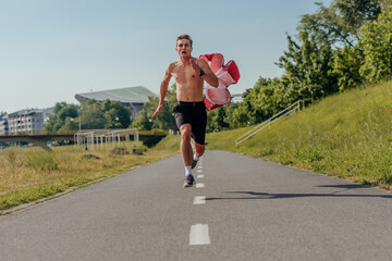 Male athlete is running shirtless with a parachute in the park