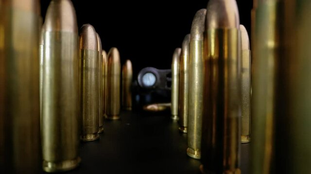 SLOW PUSH IN ON A RIFLE BARREL SURROUNDED BY RIFLE BULLETS.  4K, WIDE ANGLE MACRO SHOT.  NO PEOPLE.
