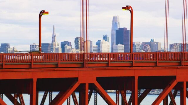 Aerial view of the magnificent Golden Gate Bridge with a cargo ship passing under it. This bridge connects the San Francisco peninsula to Marin County. US route 101 and SR 1 full of cars. Red 8K. 
