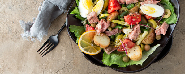 a plate of nicoise salad with tuna, egg and potatoes on the table