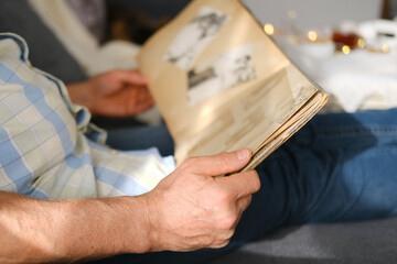 an elderly man looks through an album with old photographs, a concept of memories of youth,...