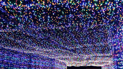 A tunnel decorated with many colorful led lights. Christmas illumination lights on the ceiling and walls create a light passage.