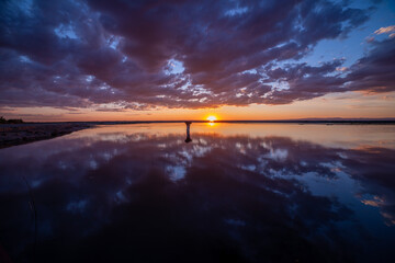 Wide-angle panorama of a scenic sunset over a lake with clouds reflection on a calm water surface, Central Oregon