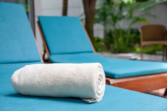 Brown pool towels are rolled up and placed on a sunbed by the pool in a pool villa in a luxury hotel
