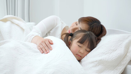 Obraz na płótnie Canvas ベッドに横たわる娘を見守る母