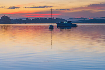 Fototapeta na wymiar Sunrise waterscape with boats, light cloud and fog