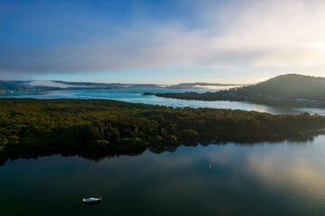Early morning aerial waterscape with boats, light cloud and fog