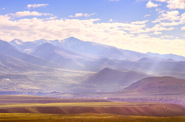 Chui Valley in the Altai Mountains. Slanting rays of light fall through the clouds on the hills and the wide plain. Siberia, Russia