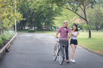 Couples hip Foster are a walk in the park with bicycles happily.