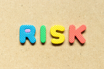 Foam alphabet letter in word risk on wood background