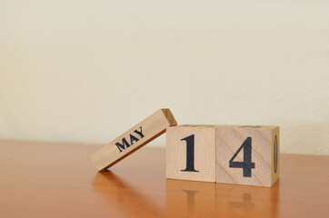 May 14, Date design with calendar cube on wooden table and white background.