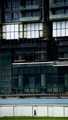 Obraz premium Lady walking alone under huge constructed building in Singapore