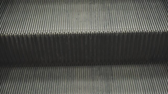 Close up 4K video of metal escalator moving down in repeating pattern shows iconic of urban life living in city with rush and patterning lifestyle. It is beautiful art background for transportation.