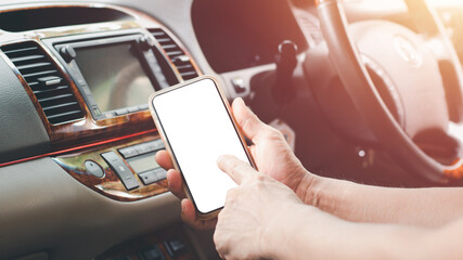 Right hand of a man holding smartphone,white screen,left hand index finger pointing to a screen protruding at car stereo,concept is a connection between new and old technology through smartphone app.